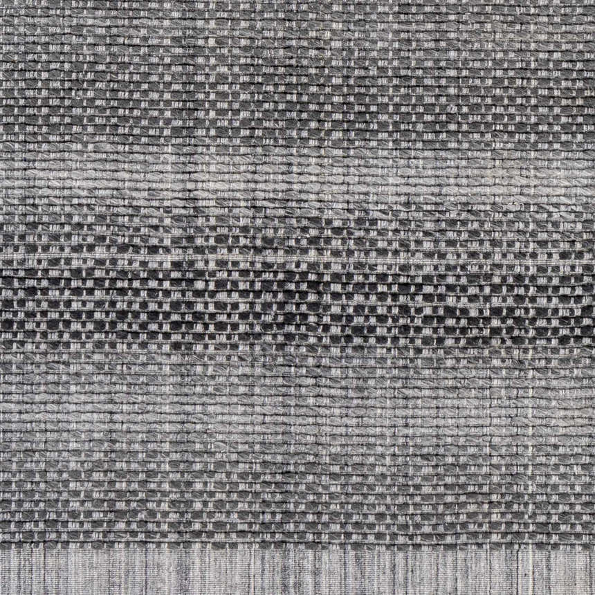 Close-up of the hand-loomed Yong Gray Rug. Features a textured, charcoal and light slate woven design. Swatch