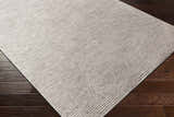 Close up of the Angie Area Rug in charcoal, featuring a contemporary striped design and viscose texture on dark wood floors. Corner