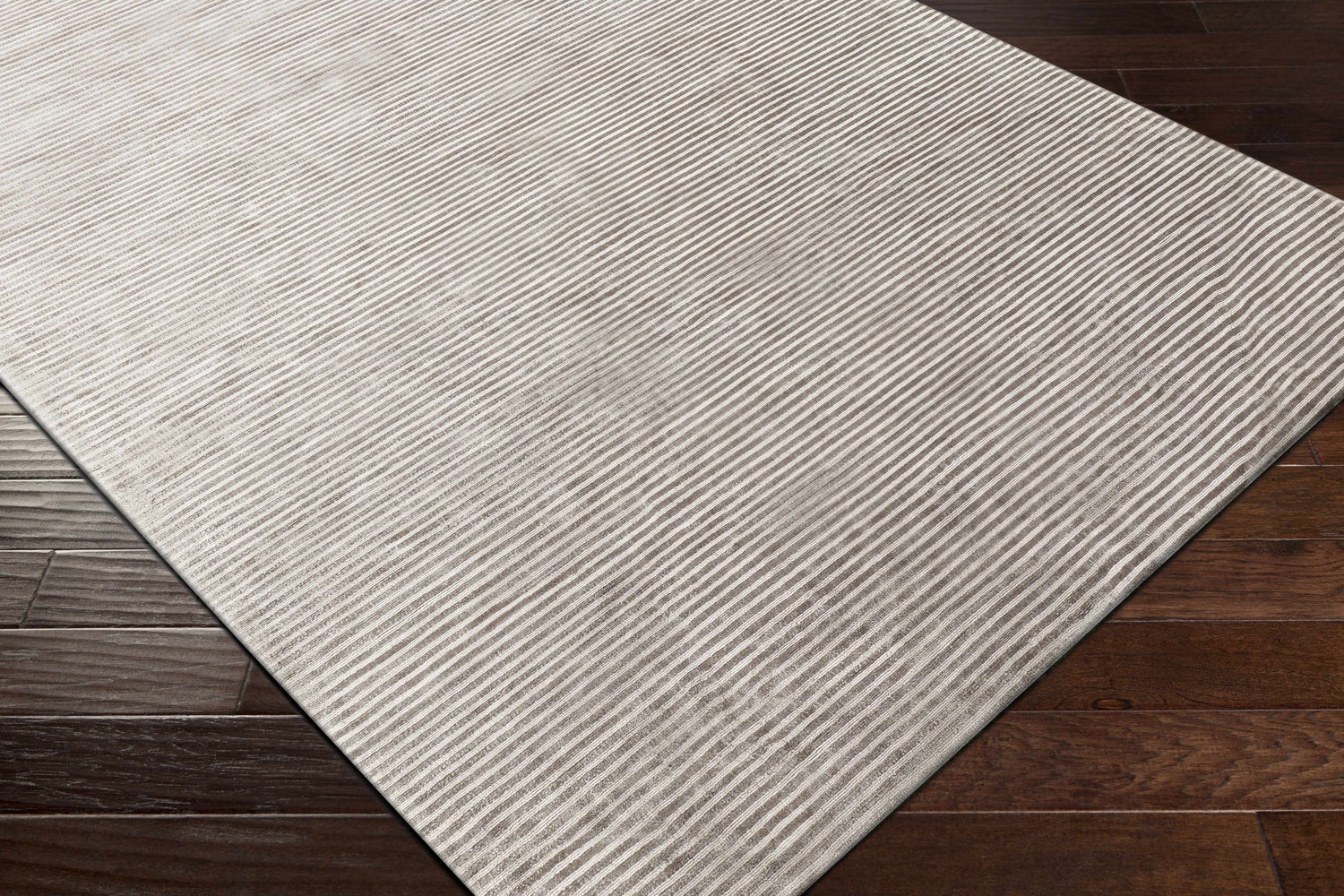 Close up of the Angie Area Rug in charcoal, featuring a contemporary striped design and viscose texture on dark wood floors. Corner
