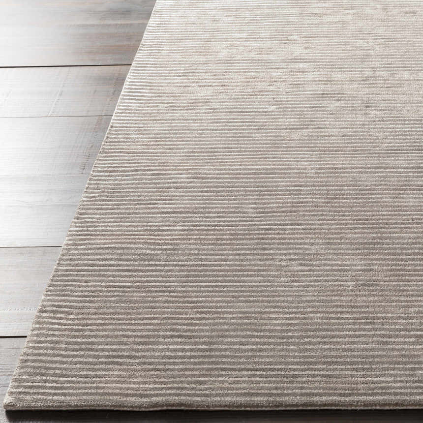 Close-up of the charcoal Angie Area Rug showing its striped pattern and soft, viscose texture on wood floors. Front