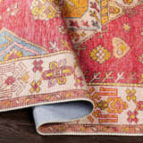 Close-up of the Anopog Washable Area Rug. Features a traditional red, yellow, and blue pattern with a farmhouse style. Fold