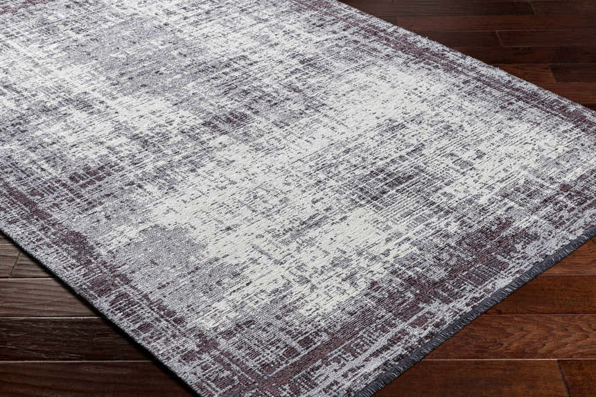 Close-up of the Binh Gray Area Rug showcasing its charcoal, cream, and slate contemporary design and chenille-polyester texture. Corner