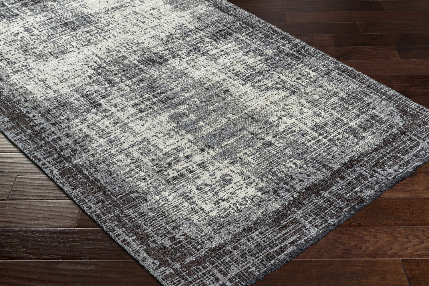 Close-up of the Binh Gray Area Rug showing its charcoal, cream, and slate contemporary design and chenille-polyester texture. Corner