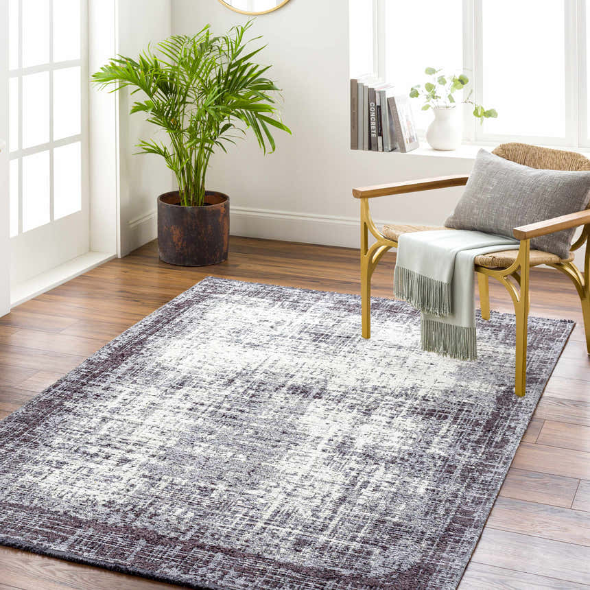 Living room scene with Binh Gray Area Rug, wood floors, straw chair, and potted plant creating a cozy, contemporary vibe. Roomscene-Rectangle
