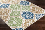 Close-up of Arecibo Clearance Rug. Hand-woven cotton rug with aqua, beige, blue, brown, and green floral pattern. Corner
