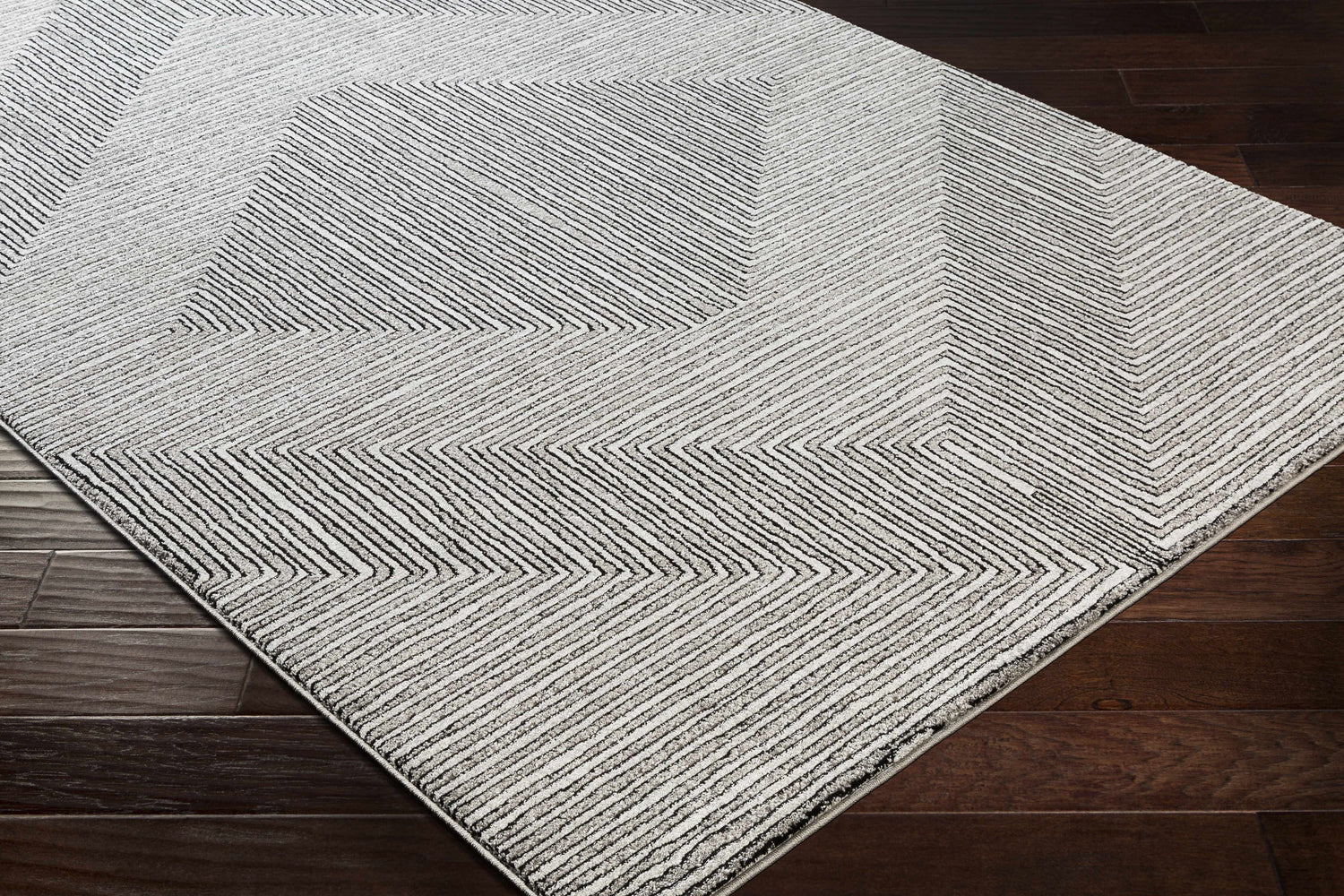 Close-up of Artois area rug. Black, cream, and gray geometric pattern on a soft, textured rug. Corner