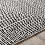 Close-up of Artois rug showing black, cream, and gray geometric chevron pattern and textured jute and polypropylene fibers. Texture
