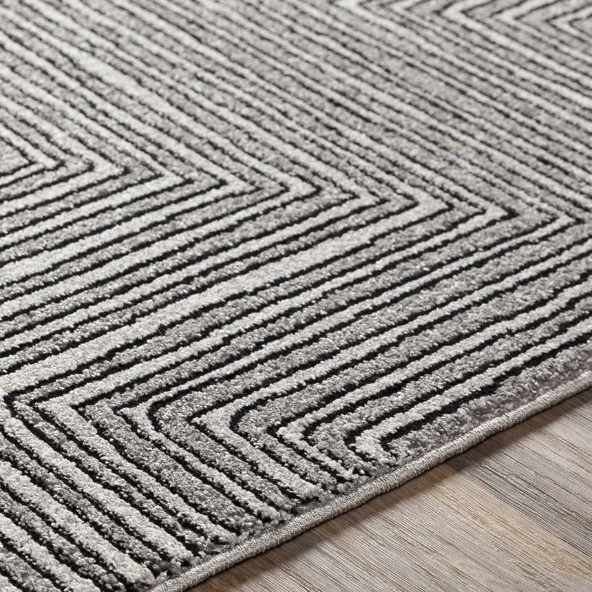 Close-up of Artois rug showing black, cream, and gray geometric chevron pattern and textured jute and polypropylene fibers. Texture