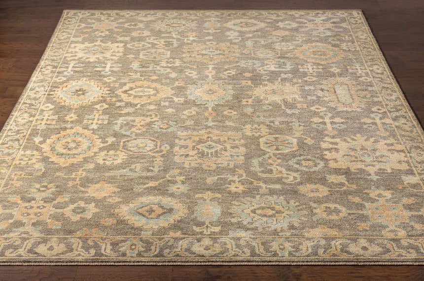 Close-up of the hand-knotted Asotin Area Rug. Features traditional burnt orange, charcoal, mustard, olive, and seafoam colors. Front