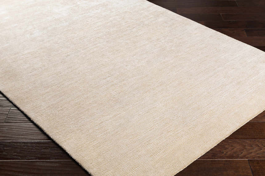 Close up of the beige Atlas Carpet showing texture and hand knotted construction. Corner