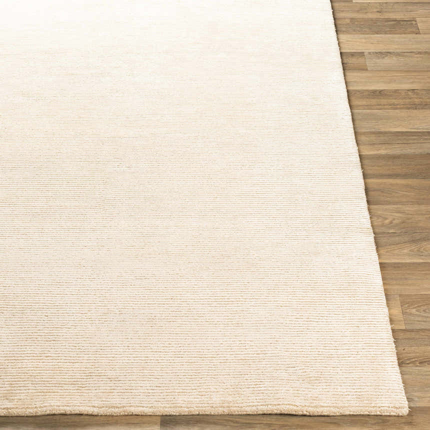 Close-up of the beige Atlas Carpet showing its subtle horizontal texture and hand-knotted construction. Front