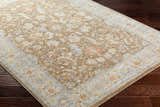 Close-up of Atli Thick Luxe Area Rug in amber, brown, pink, gray and taupe on dark wood floor. Floral, traditional pattern. Corner