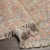 Close-up of the hand woven Atulayan Premium Rug. Features a colorful pattern and knotted fringe. Bohemian style. Fold