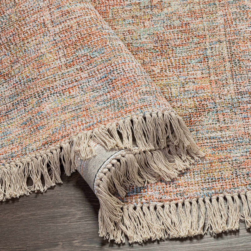 Close-up of the hand woven Atulayan Premium Rug. Features a colorful pattern and knotted fringe. Bohemian style. Fold