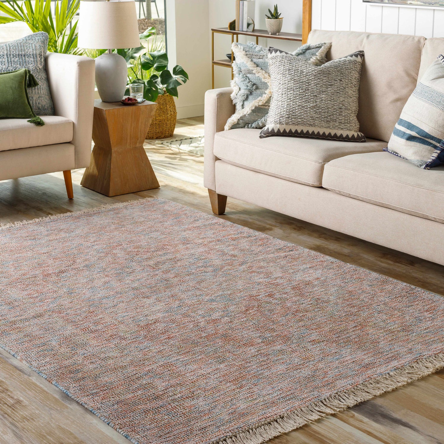 Living room scene with a fringed Atulayan Premium Rug in blue, burgundy, and coral tones, styled with a beige sofa and armchair. Roomscene-Rectangle