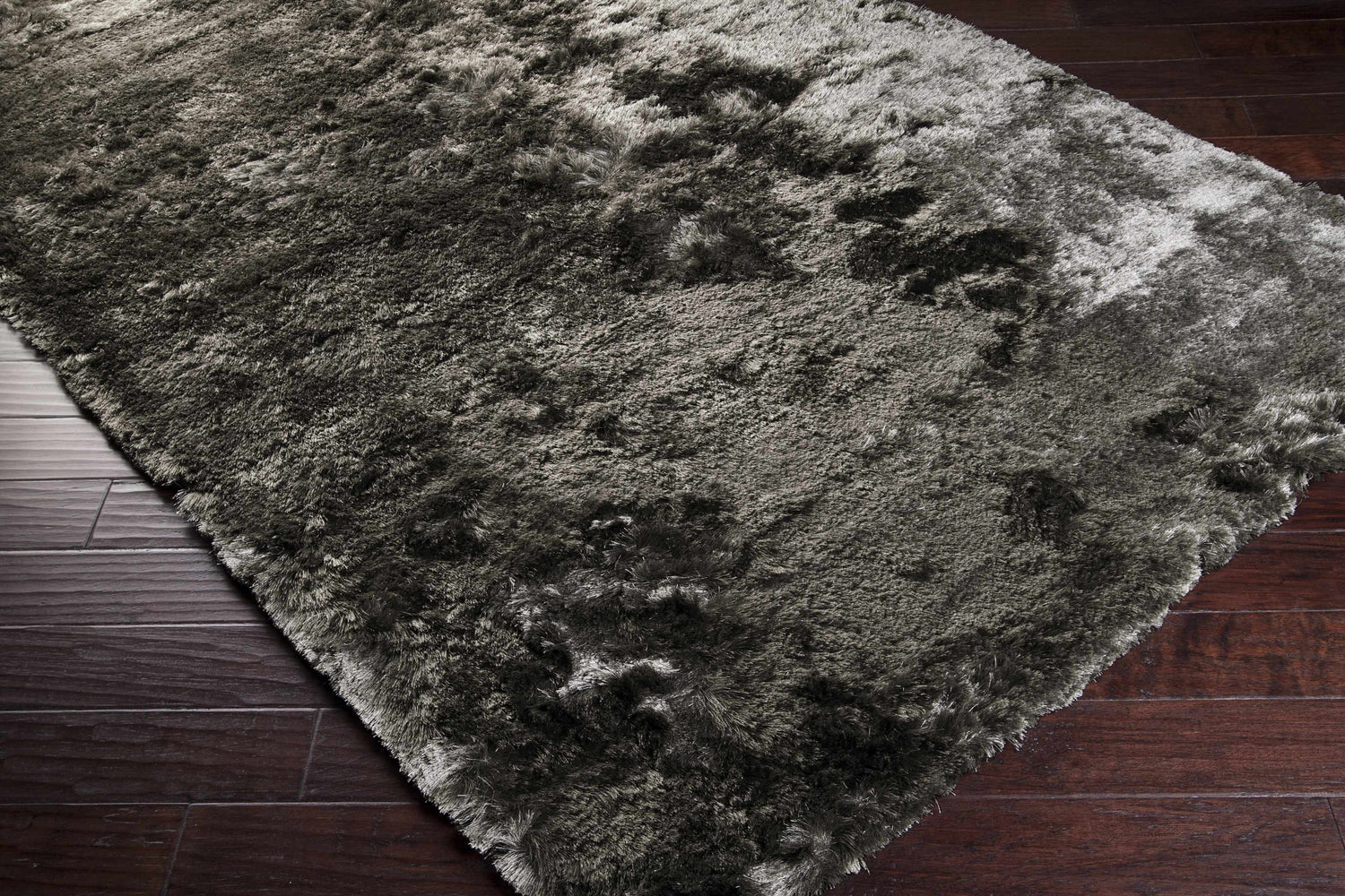 Close-up of a teal and ink blue Auxier Area Rug showing its shag texture on dark wood flooring. Corner