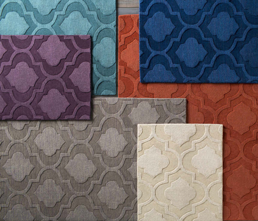 Close-up of Kake Carpet in tan, blue, orange, purple, and gray. Wool rugs feature a contemporary quatrefoil pattern. Styleshot