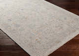 Close-up of the Ayarn Thick Luxe Statement Rug, a traditional rug in brown, teal, sage and gray on dark wood floors. Corner
