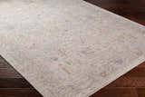Close-up of Ayarn Thick Luxe Statement Rug in brown, charcoal, teal, sage, and gray on dark wood floor. Traditional style. Corner