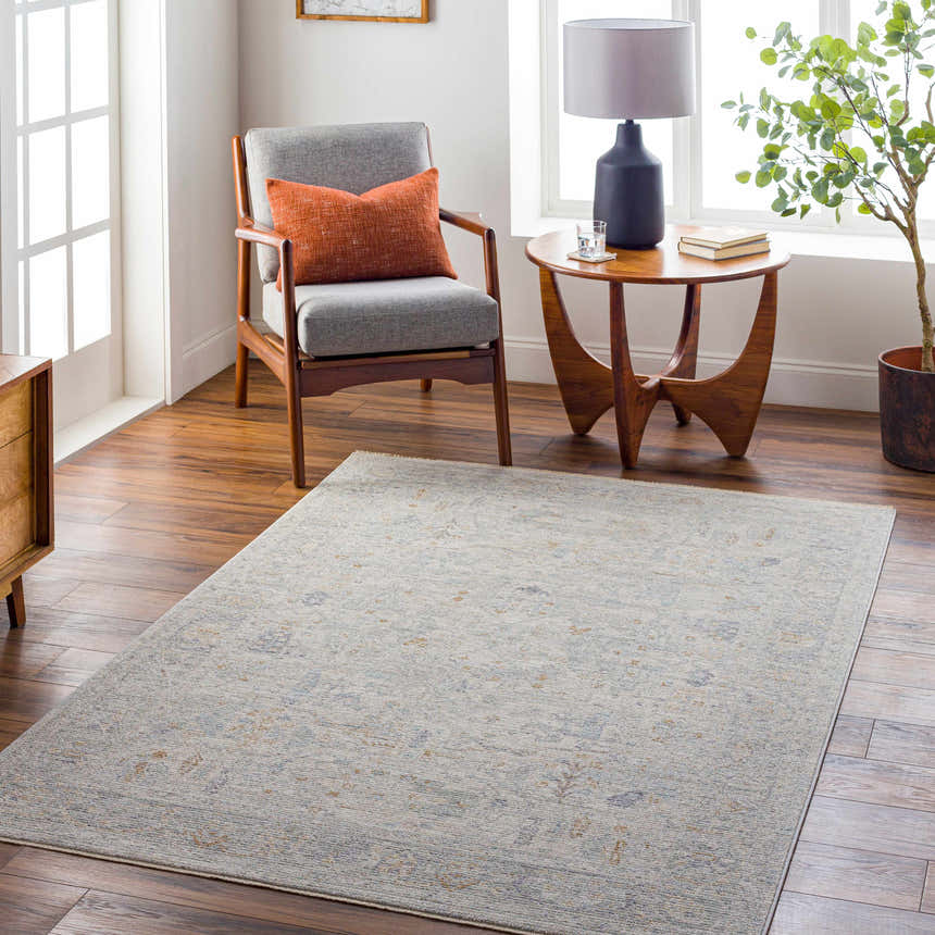 Living room scene with a gray chair, wood side table, and the Ayarn Thick Luxe Statement Rug in gray and brown tones. Roomscene-Rectangle