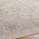 Close-up of the Ayarn Thick Luxe Statement Rug. Beige rug with brown, teal, and gray traditional pattern. Texture