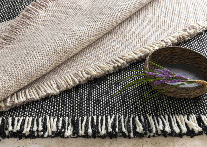 Close-up of the Boyden Black Area Rug with Tassels, showing its woven texture and black, cream, and gray colors. Styleshot