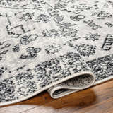 Close up of the Badar Area Rug showing its charcoal and gray traditional pattern. Fold
