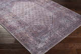 Close-up of the Dusty Pink Bagacay Distressed Washable Area Rug showing its oriental pattern and colors on a dark wood floor. Corner
