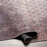 Close-up of the Dusty Pink Bagacay Distressed Washable Area Rug showing its cream, pink, and blue oriental pattern. Fold