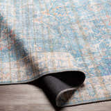 Close-up of the Bagontapay Washable Area Rug. Blue, cream, and light brown oriental pattern with a textured chenille feel. Fold