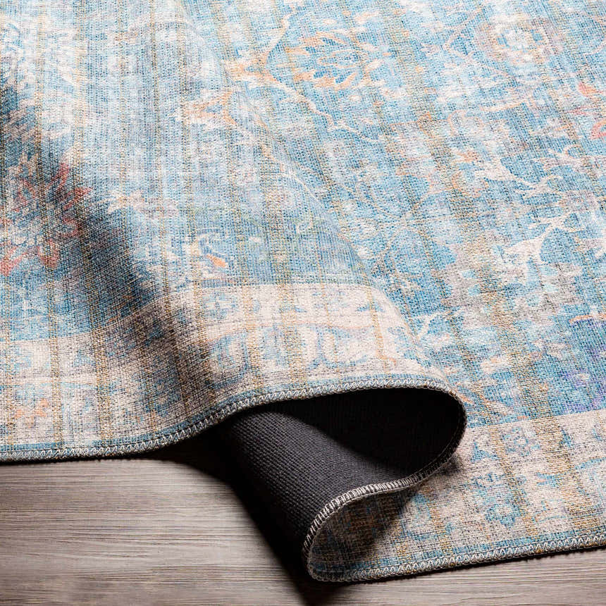 Close-up of the Bagontapay Washable Area Rug. Blue, cream, and light brown oriental pattern with a textured chenille feel. Fold