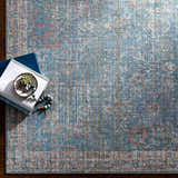 Close-up of the blue and cream Bagontapay Washable Area Rug with traditional floral pattern and books. Styleshot