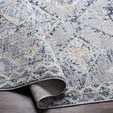 Close-up of Balamban Area Rug in brick red, cream, denim, gray, light beige, and navy. Bohemian style polyester rug. Fold