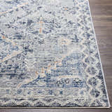 Close-up of the Balamban Area Rug. Features a distressed bohemian pattern in cream, denim, gray, and light beige. Front