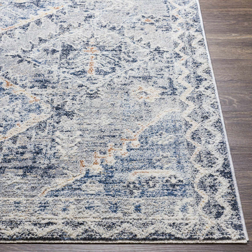 Close-up of the Balamban Area Rug. Features a distressed bohemian pattern in cream, denim, gray, and light beige. Front