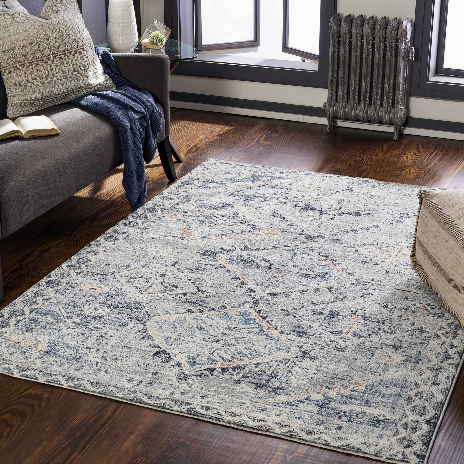 Living room scene with a Balamban Area Rug in brick red, cream, denim, and gray colors on a dark wood floor. Roomscene-Rectangle
