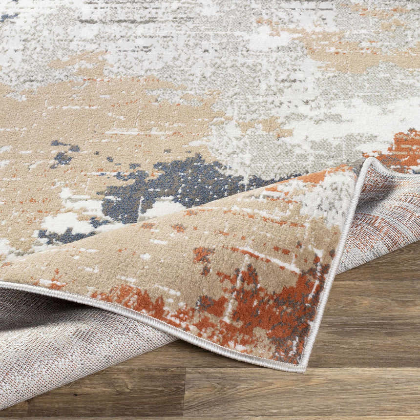 Close-up of the Balerno Area Rug showing its charcoal, blue, gray, mustard, terracotta, and white contemporary design. Fold