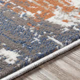 Close-up of the Balerno Area Rug. Contemporary design in charcoal, blue, gray, mustard, terracotta, and white. Machine woven texture. Texture