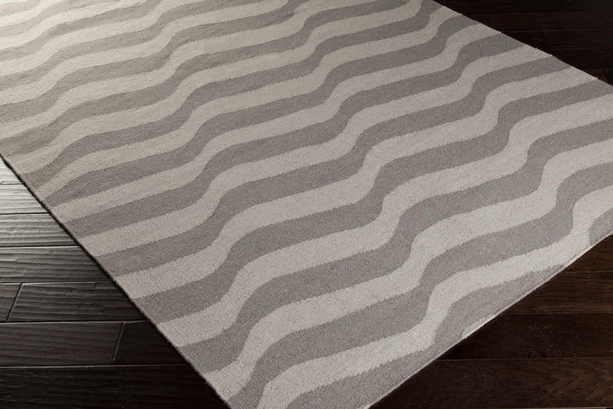 Close-up of the Balsam Area Rug. Light gray and slate wavy stripes on a hand-woven wool rug. Contemporary style. Corner