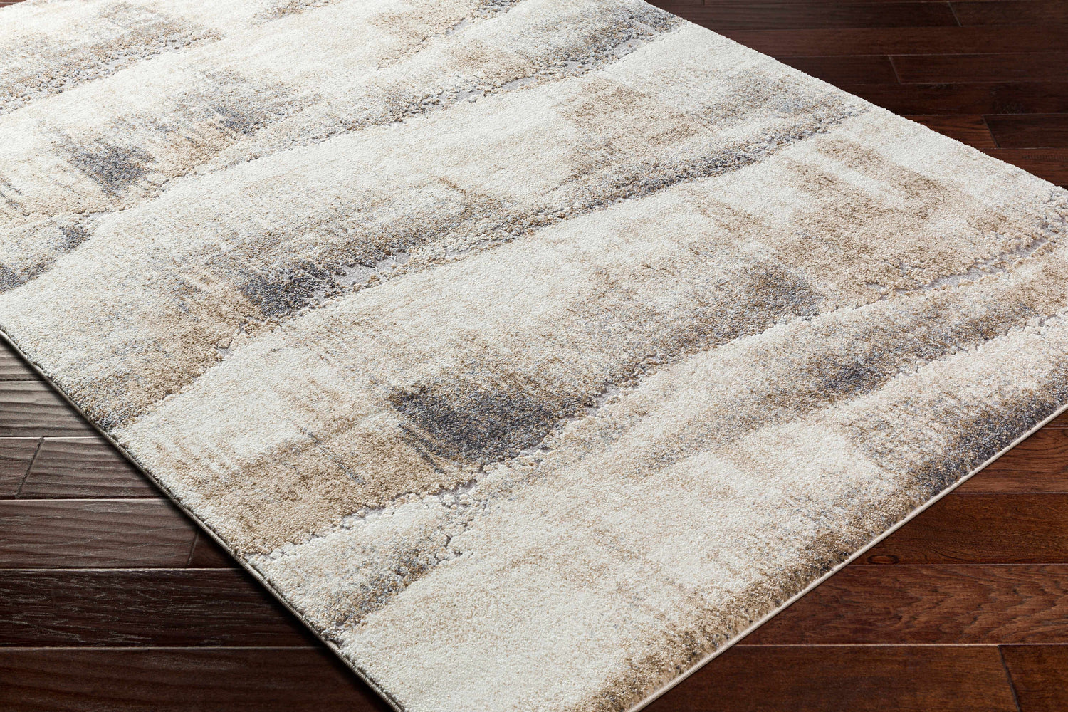 Close-up of the Banji Abstract Waves Area Rug. Beige, gray, and brown tones create a contemporary pattern. Corner
