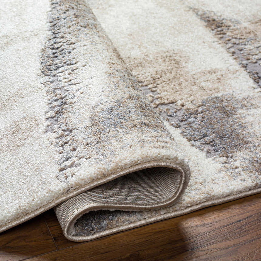 Close-up of the Banji Abstract Waves Area Rug showing its beige, gray, and brown textured pattern and machine-woven construction. Fold