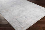 Close-up of the Baranduda Abstract Gray Luxe Rug showing its charcoal, blue, beige, and yellow abstract design. Corner