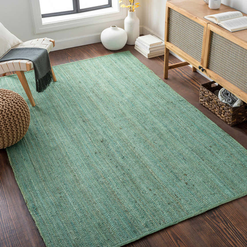 Living room scene with a Barksdale Green hand woven jute rug, wood floors, and natural decor. Roomscene-Rectangle