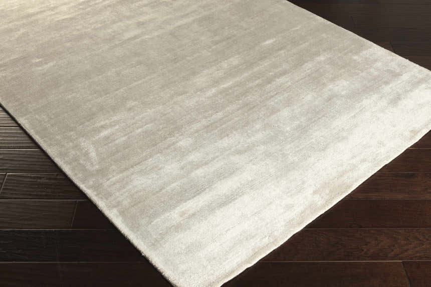 Close-up of the white Barree Area Carpet showing its contemporary design and soft, viscose texture on dark wood flooring. Corner