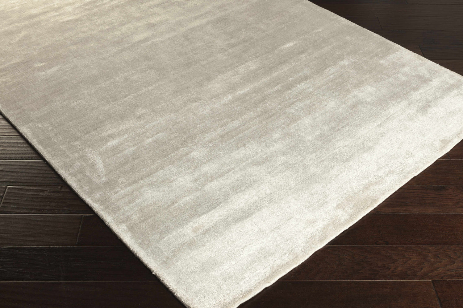 Close-up of the white Barree Area Carpet showing its contemporary design and soft, viscose texture on dark wood flooring. Corner