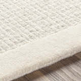 Close-up of the hand-tufted Barrow Wool Rug. Cream and light gray wool fibers show texture and striped pattern. Texture