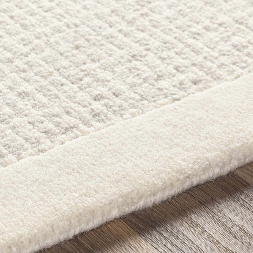 Close-up of the hand-tufted Barrow Wool Rug. Cream and light gray wool fibers show texture and striped pattern. Texture