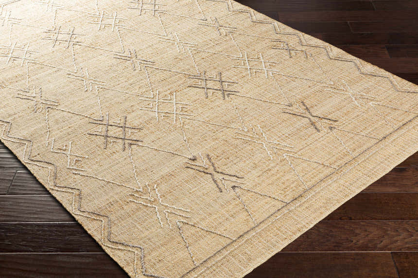 Close-up of Beatrice Area Rug. Beige jute rug with gray and off-white geometric, hand-woven design. Farmhouse style. Corner