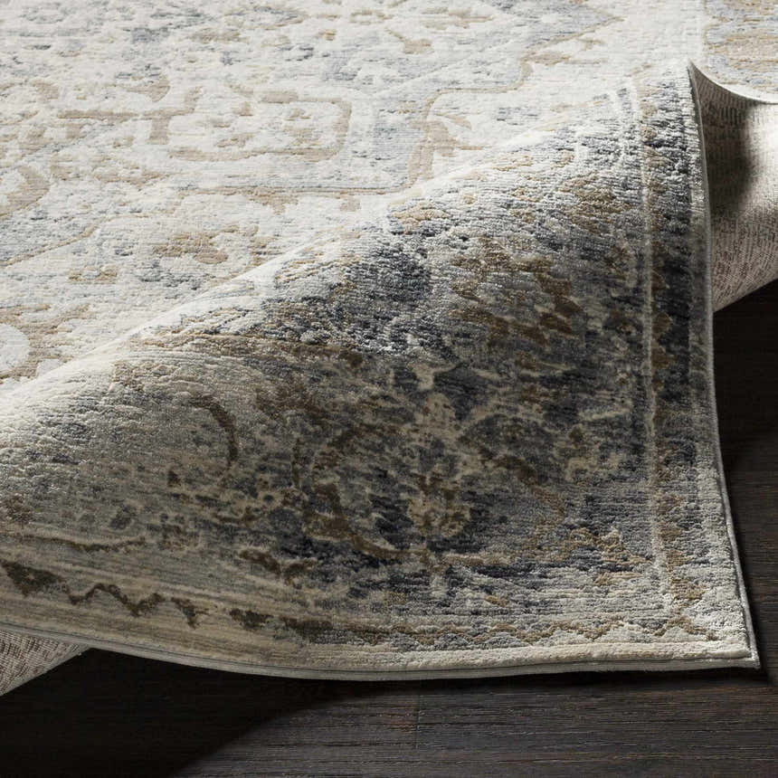 Close-up of the Beebe Luxe Machine Area Rug showing its ivory, gray, and brown traditional pattern and soft texture. Fold