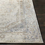 Close up of the Beebe Luxe Area Rug featuring a traditional pattern in ivory, gray, and brown on dark wood floors. Front